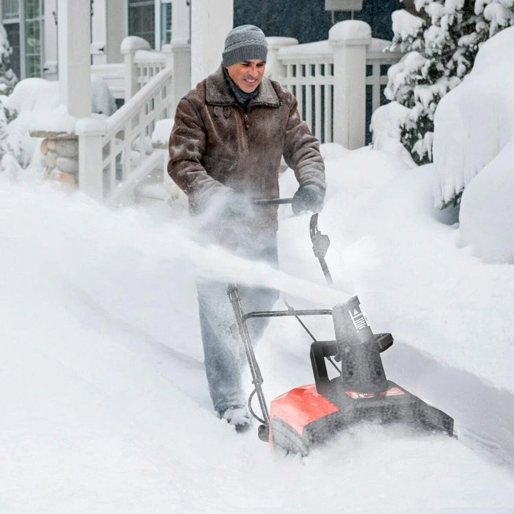 Person using a snow blower to clear snow in front of a house