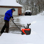 Person using a snow blower to clear snow from a driveway